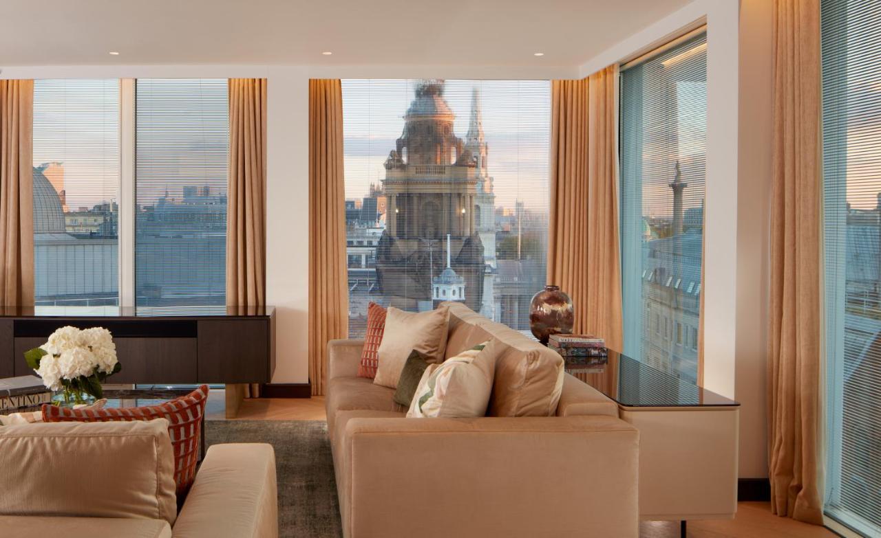 โรงแรมเซนต์ มาร์ติน เลน ลอนดอน ภายนอก รูปภาพ The photo depicts a stylish and modern living room space. The room features large windows with sheer curtains, allowing natural light to fill the area. A plush beige sofa with decorative cushions is positioned centrally, creating a cozy atmosphere. I