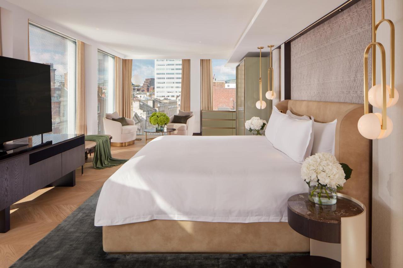 โรงแรมเซนต์ มาร์ติน เลน ลอนดอน ภายนอก รูปภาพ The photo shows a modern hotel room featuring a large, comfortable bed with white bedding. The room has large windows that provide natural light and a view of the cityscape outside. There is a stylish flat-screen TV mounted on the wall and a dark woo