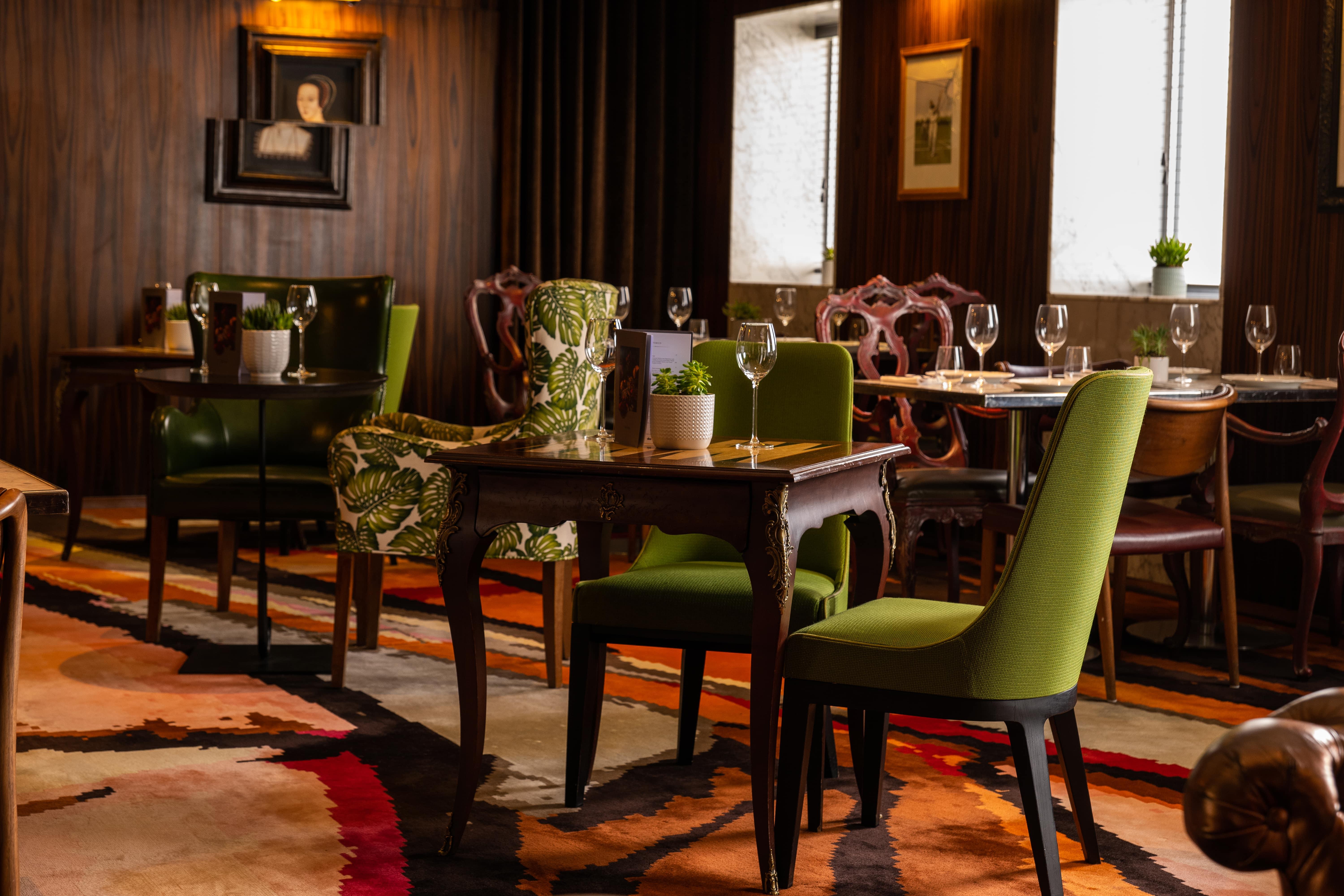 โรงแรมเซนต์ มาร์ติน เลน ลอนดอน ภายนอก รูปภาพ The image depicts an elegant dining area with a blend of classic and contemporary design elements. There are several tables arranged neatly, each accompanied by stylish chairs. Some chairs have vibrant green upholstery and unique patterns, while othe