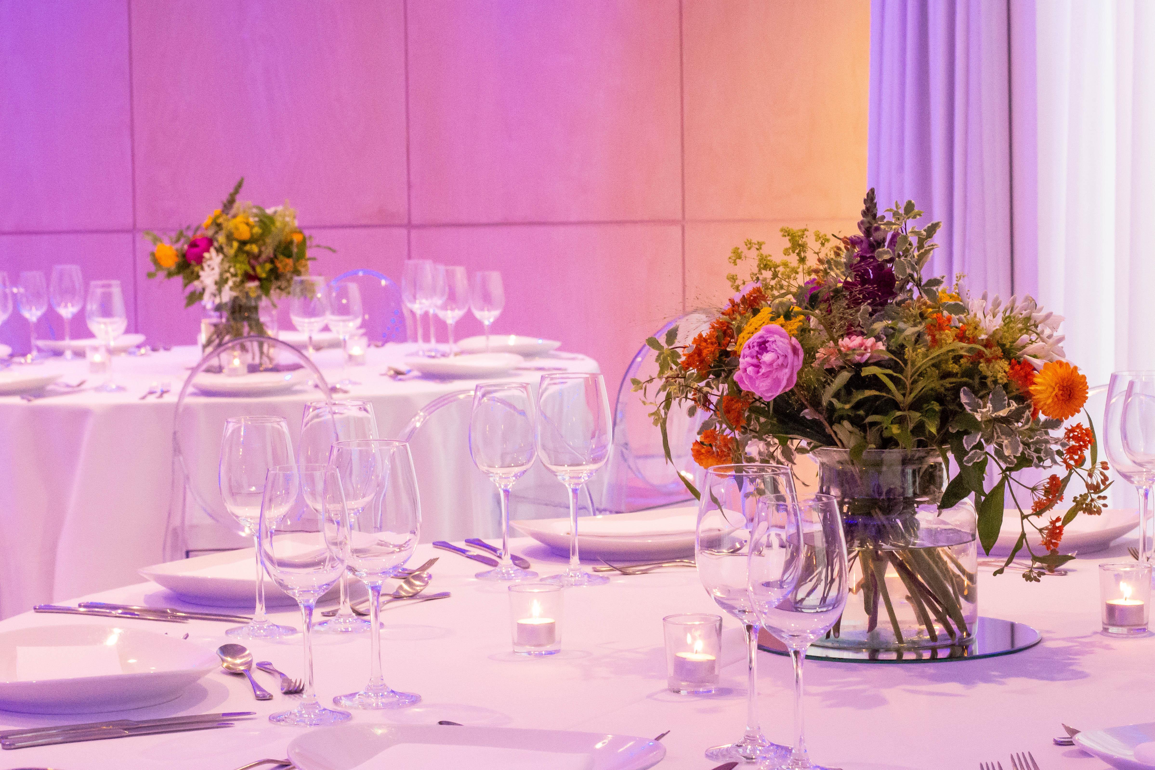 โรงแรมเซนต์ มาร์ติน เลน ลอนดอน ภายนอก รูปภาพ The photo shows a beautifully arranged dining setup, likely for an event or celebration. The tables are elegantly dressed with white tablecloths and feature floral centerpieces in clear vases. The bouquets consist of a variety of colorful flowers, ad