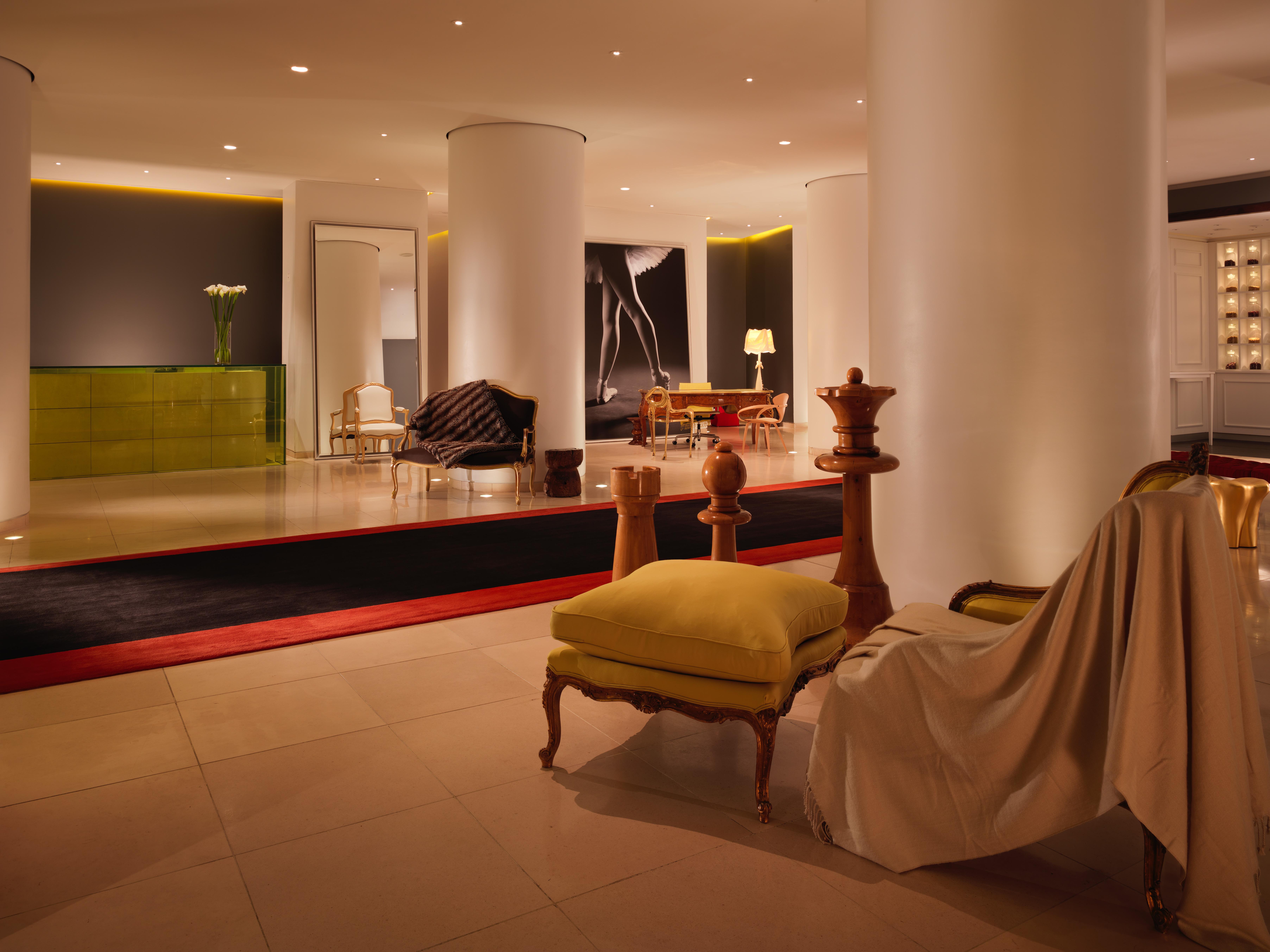 โรงแรมเซนต์ มาร์ติน เลน ลอนดอน ภายนอก รูปภาพ The photo shows a modern, stylish hotel lobby. It features a spacious open area with sleek white columns and subtle lighting. There are various seating arrangements, including a sofa and armchairs, with a mix of contemporary and classic design elemen