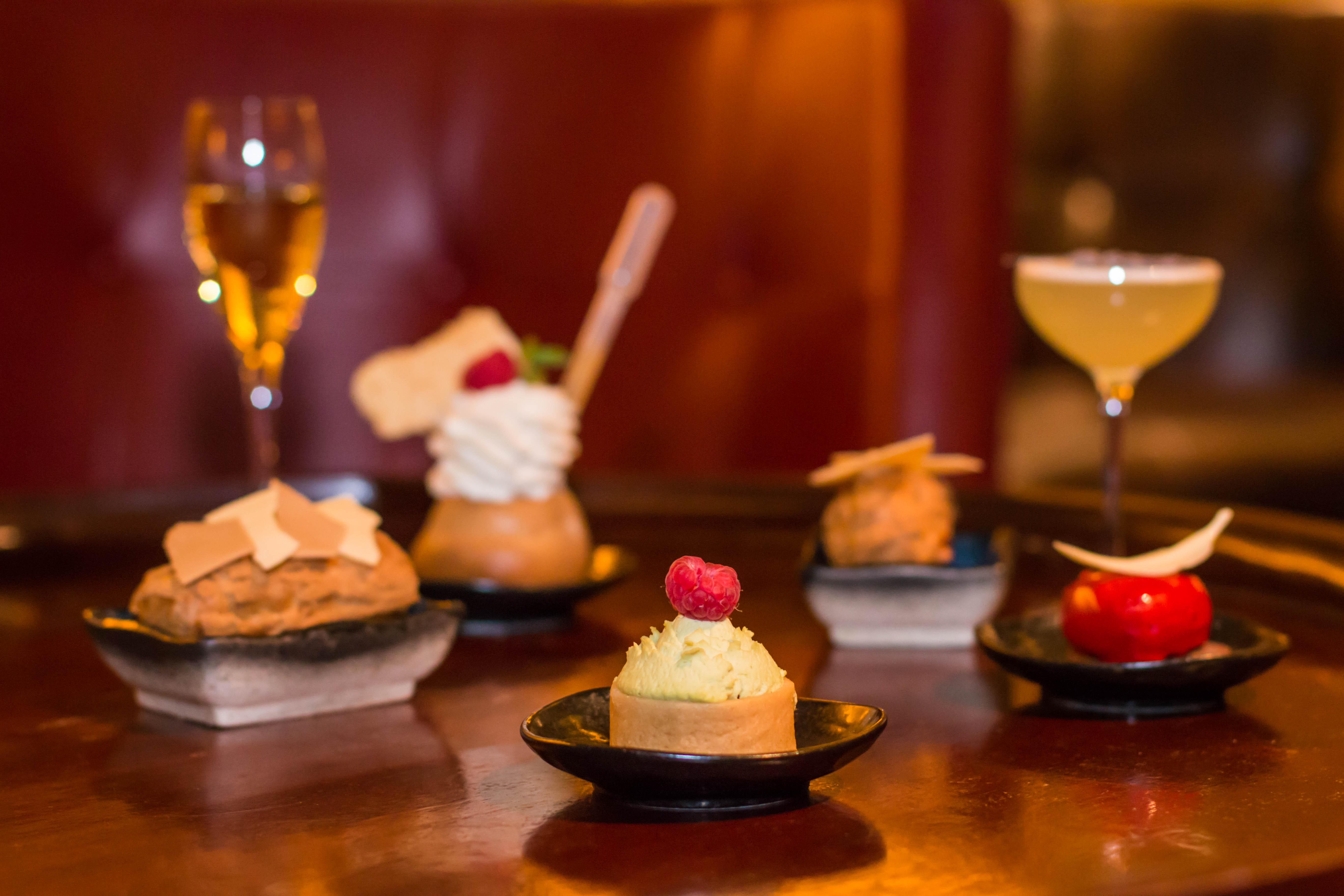 โรงแรมเซนต์ มาร์ติน เลน ลอนดอน ภายนอก รูปภาพ The photo showcases a variety of elegantly presented desserts and drinks. In the foreground, there are five small plates, each containing a different dessert. The desserts include a creamy cake topped with a raspberry, a small pastry with a swirl of 