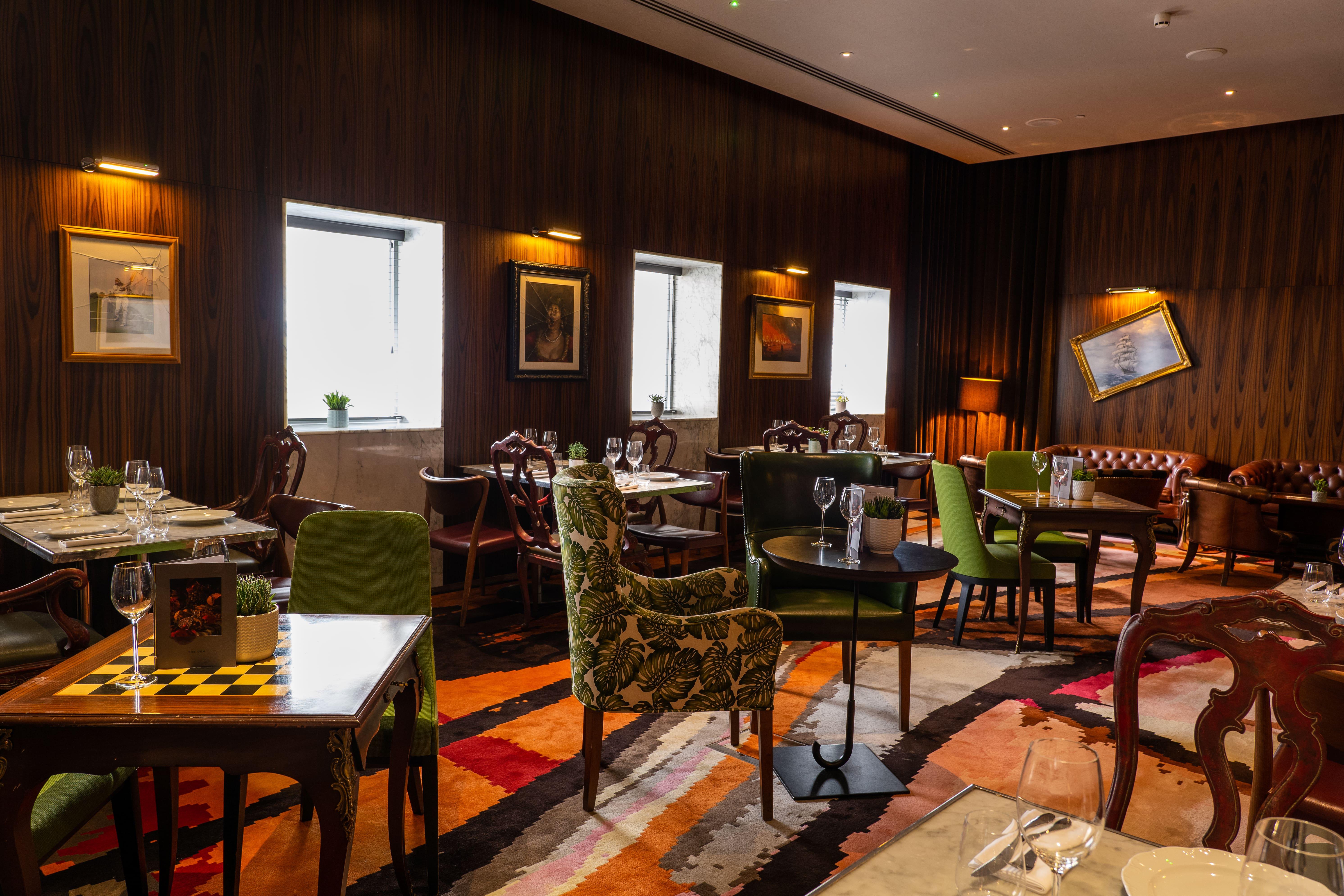 โรงแรมเซนต์ มาร์ติน เลน ลอนดอน ภายนอก รูปภาพ The photo depicts an elegantly designed restaurant interior. It features a combination of wooden walls and warm lighting, creating a cozy atmosphere. The seating comprises various styles of chairs, some with colorful upholstery and patterns. Tables a