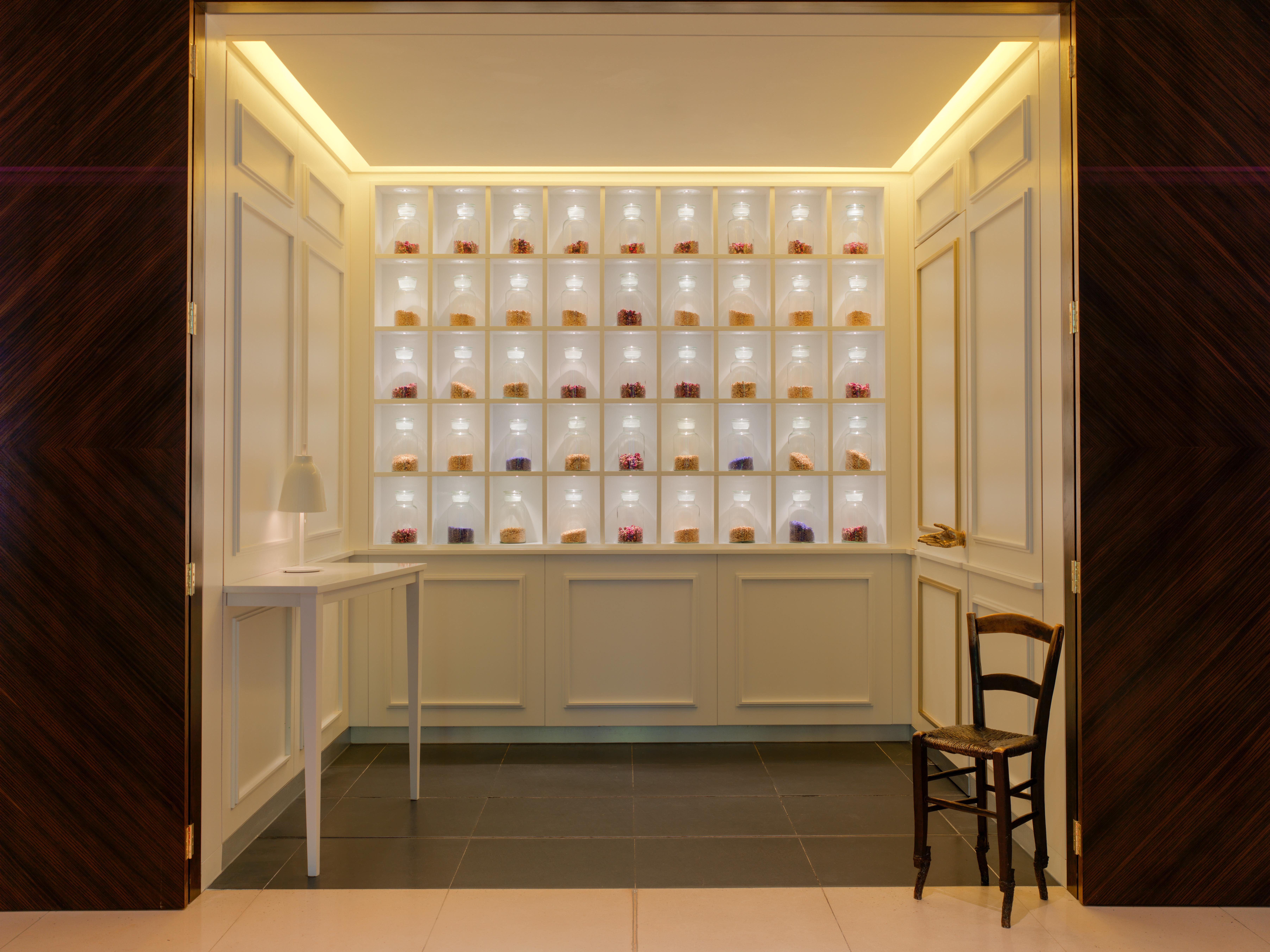 โรงแรมเซนต์ มาร์ติน เลน ลอนดอน ภายนอก รูปภาพ The photo shows an elegant interior space that features a display wall with multiple shelves. Each shelf is illuminated, showcasing a variety of small items, likely decorative or artisanal products. The wall is light-colored, creating a bright atmosp