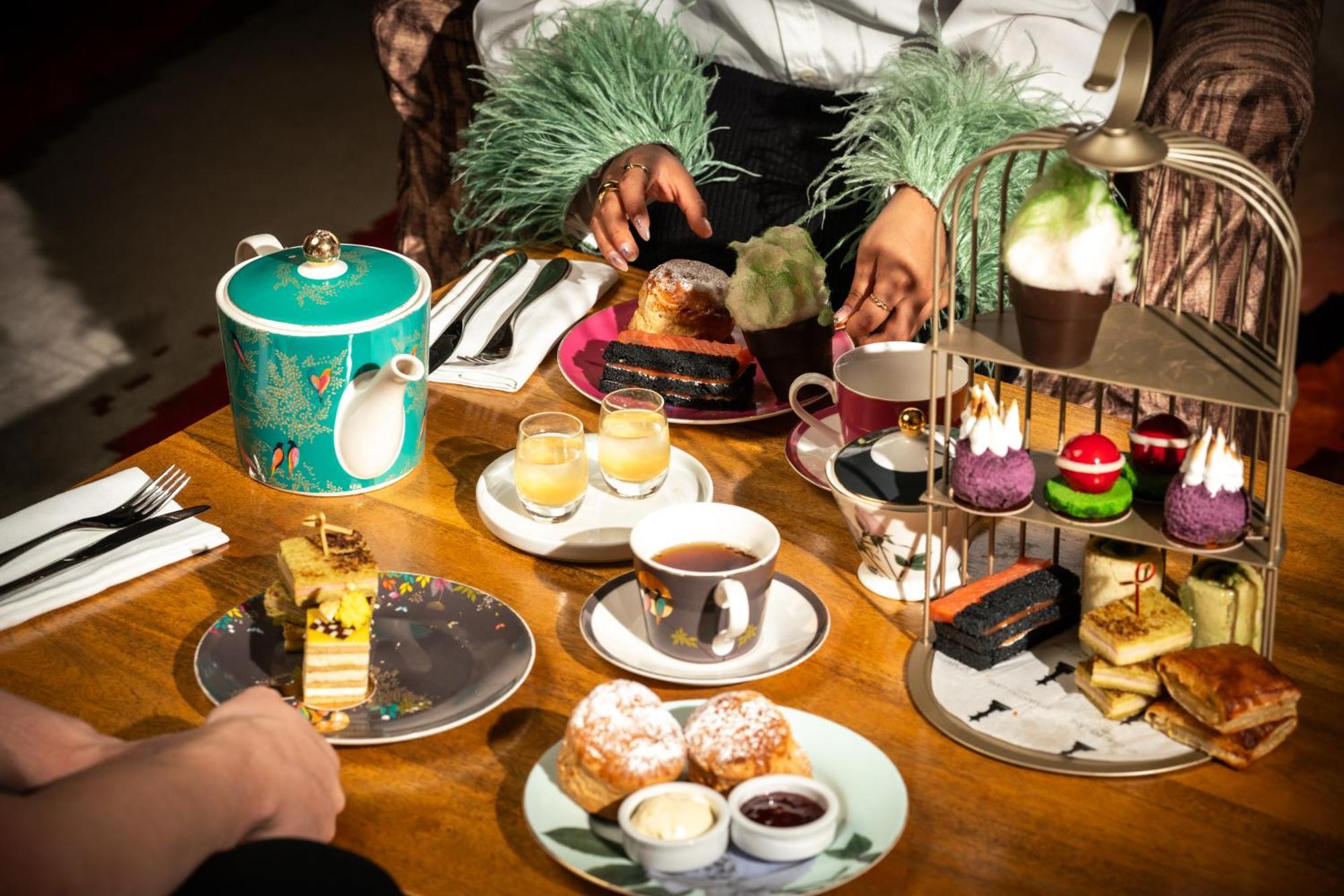โรงแรมเซนต์ มาร์ติน เลน ลอนดอน ภายนอก รูปภาพ The photo features a beautifully arranged afternoon tea setting. In the center, there's an elegant tiered stand filled with various desserts, including colorful cupcakes and small pastries. Surrounding the stand are plates with additional treats, suc
