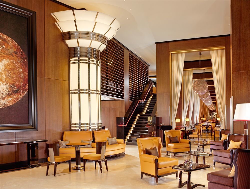 โรงแรมเซนต์ มาร์ติน เลน ลอนดอน ภายนอก รูปภาพ The photo depicts a sophisticated and elegant hotel lobby. The interior features a modern design with polished wooden accents and warm lighting. In the center, there is a large, stylish column with art deco elements. Surrounding the column are plush 