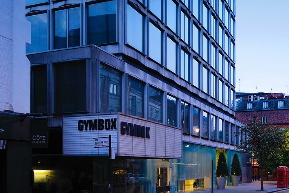 โรงแรมเซนต์ มาร์ติน เลน ลอนดอน ภายนอก รูปภาพ The image shows a modern building with a distinctive architectural design. The facade features large glass windows, and the lower section includes a sign that reads "GYMBOX." There appears to be some greenery in front of the building, and the scene i